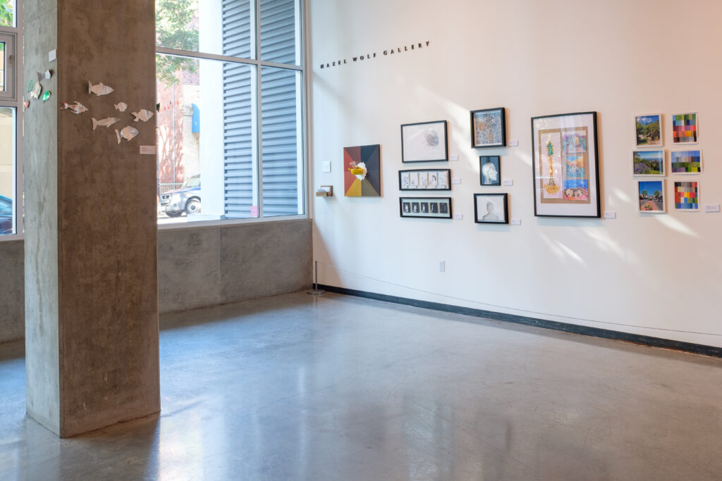 View into a gallery with artwork framed and hung on the right side wall