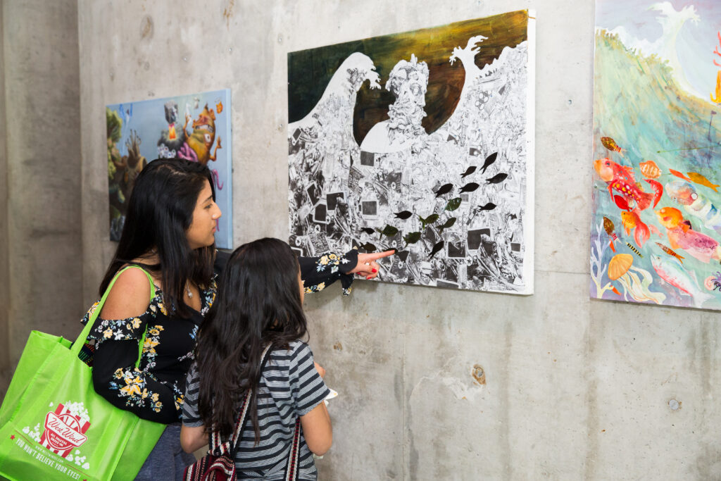 2 people looking at gallery wall with paintings hung