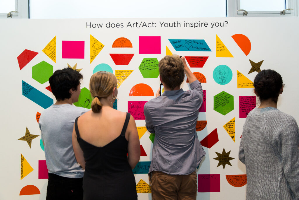 People interacting with gallery wall artwork