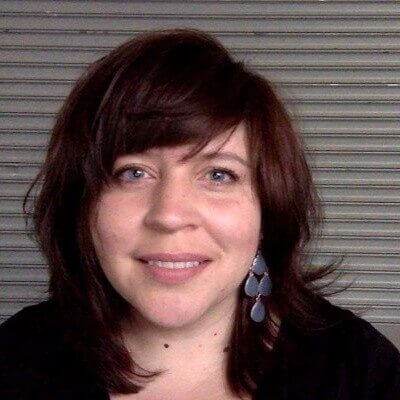 Brown haired woman wearing black shirt against a striped gray background