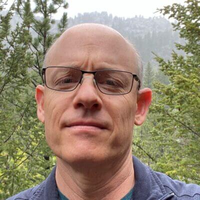 blad white man with dark rim glasses against trees and forest