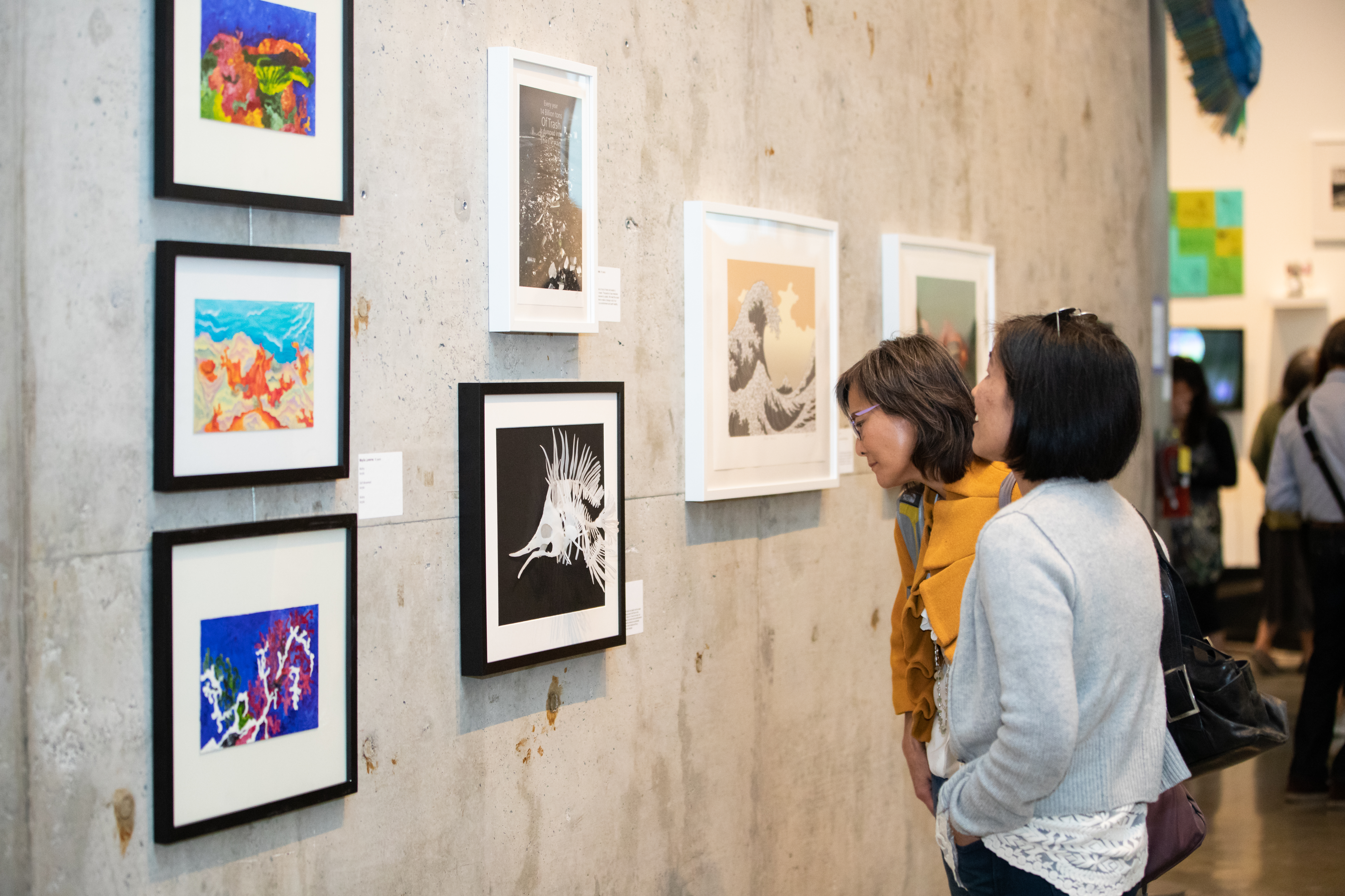 2 people looking at gallery wall with paintings hung