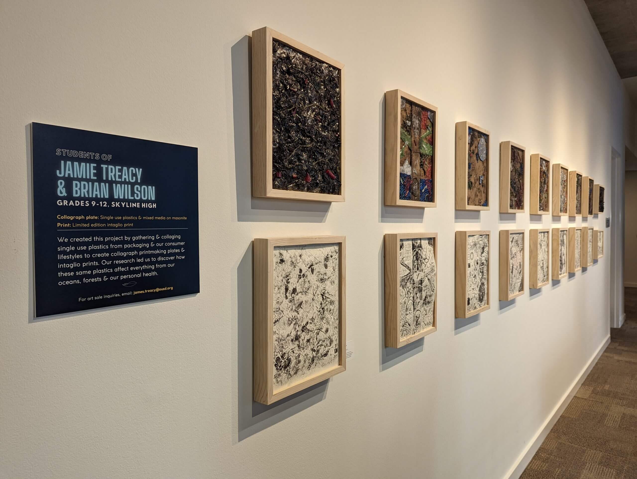 teacher name plaque with framed artworks against a gray gallery wall