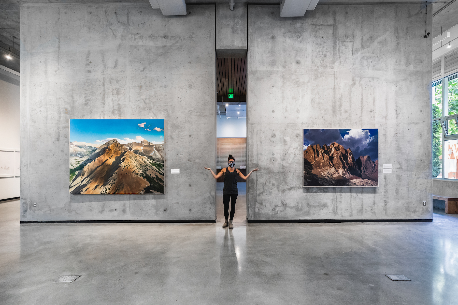 A person stands between concrete walls at the Brower Center with large landscape paintings
