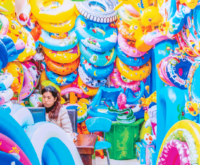 multicolored plastic inflatables crowd out a young woman bored in a store