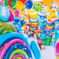 multicolored plastic inflatables crowd out a young woman bored in a store