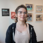 Rachel Kantor, Art/Act: Youth teacher, smiling in front of her class' collage work