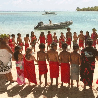 Pacific Islanders holding hands in a circle on a beach